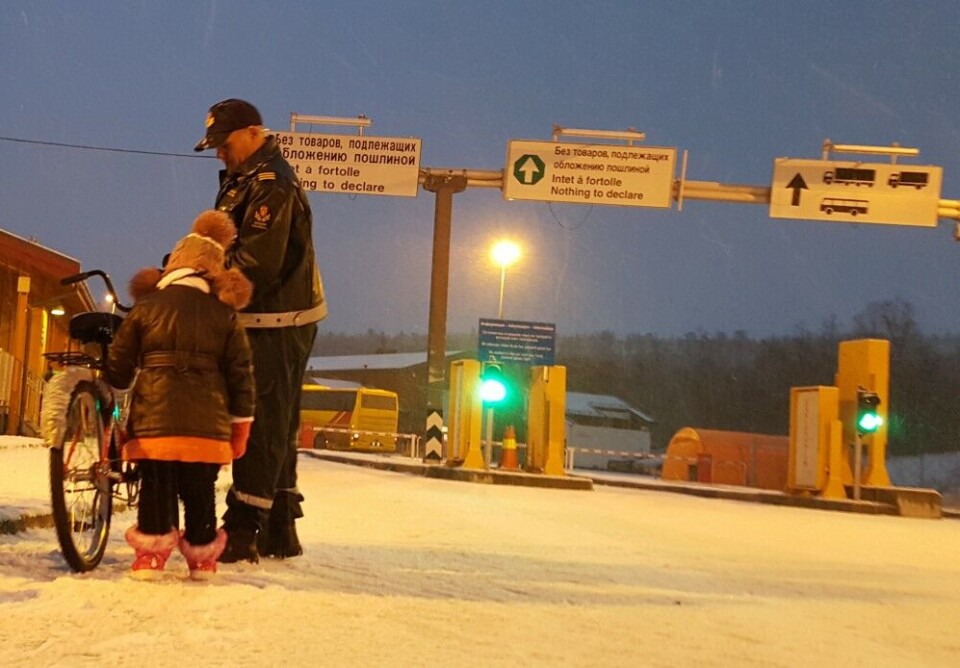 Immigration officer assists this girl with the bike she, her parents, and little brother arrived with at Storskog. Photo: Thomas Nilsen