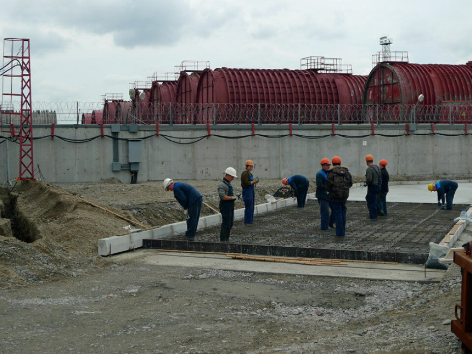 Construction workers at the new storage and processing plant for radioactive waste in Saida Bay. Reactor compartments from submarines behind the fence. Photo: Thomas Nilsen