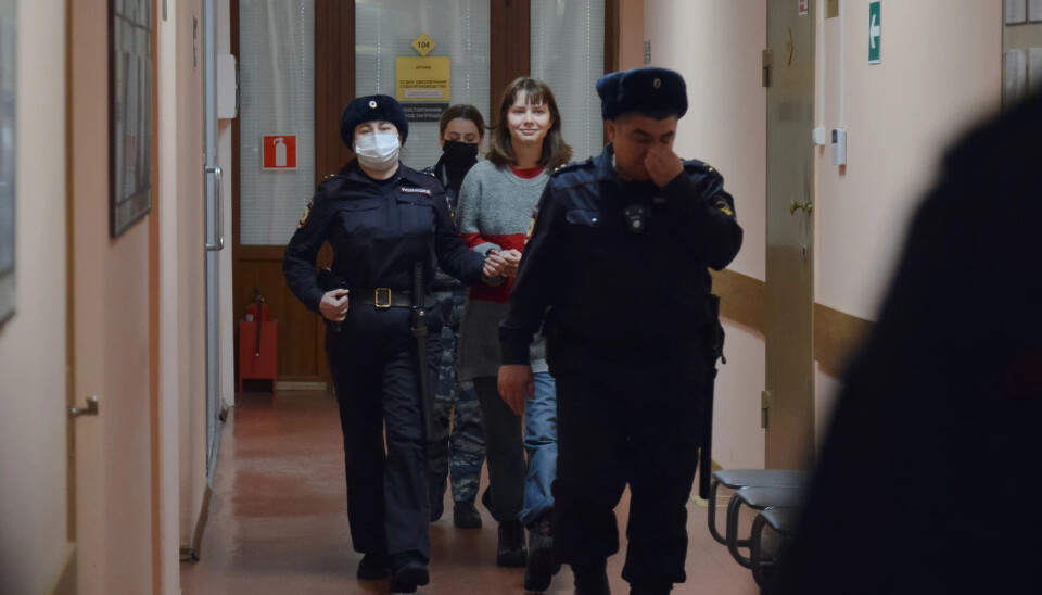 A handcuffed, but smiling, Olesya Krivtsova was taken to the courtroom by three armed police officers. Photo courtesy of 29.ru
