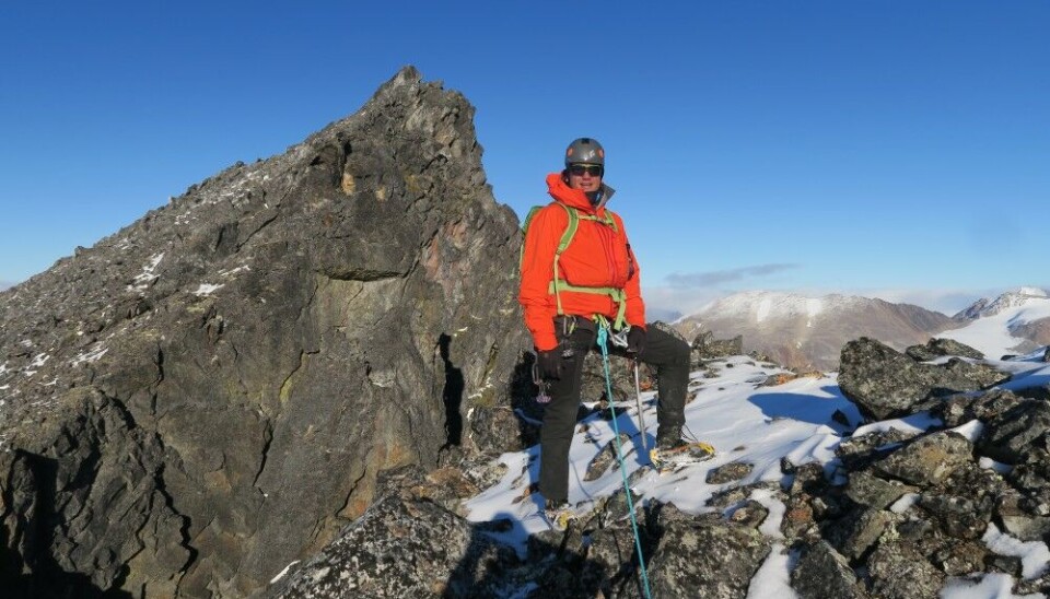 Andrey Yakunin smiles to the photographer as he nears the peak high up the mountain between Magdelenefjorden and Smeerenburgfjorden at Albert I Land north on Spitsbergen.
