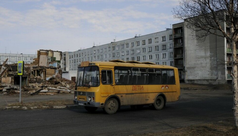 Желтый школьный автобус перед одним из двух многоквартирных домов, в которых все еще живут люди.