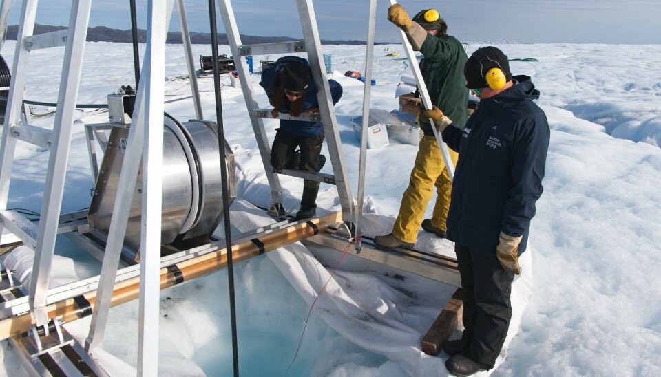 Scientists peering into the depths of the Greenland ice sheet. Photo: Henry Patton