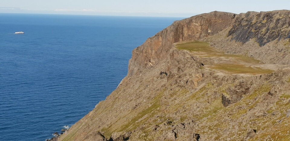 “Rockslide at Reinbenkan, with a volume significantly larger than 10 000 000 cubic metres. The sliding surface exposed at the top is over 80 metres high. Reinbenkan is located on the northeastern shore of Porsangerfjorden. In the background, a cruise ship sails on the Barents Sea. Photo: Reginald Hermanns / NGU”