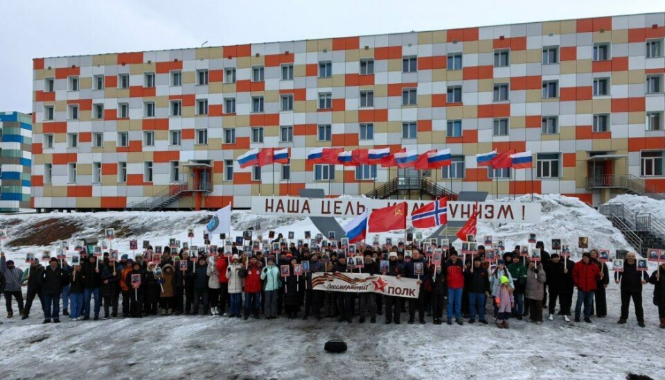 The 'Immortal Regiment' gathered for a group photo in front of the Soviet slogan in Barentsburg reading 'Our goal is communism'.