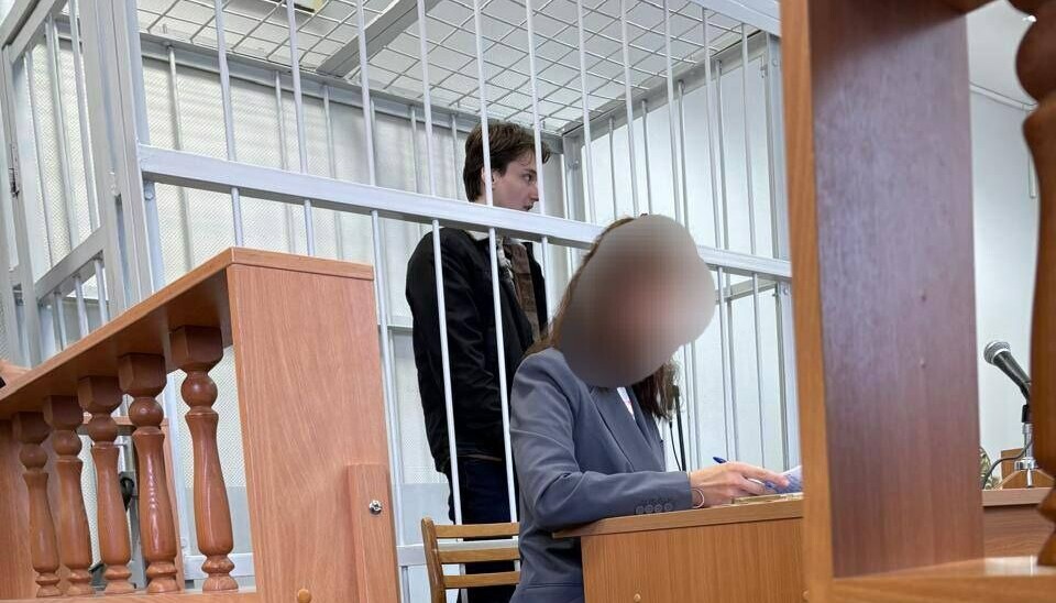 Люди в военной форме сопровождали юношу при входе в суд.